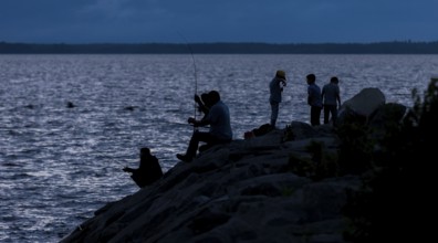 Group of people fishing at night, silhouetted against the water in Ottawa, Ontario, Canada, North