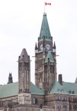 The Canadian parliament building with a clock tower and green roof under an overcast sky in Ottawa,