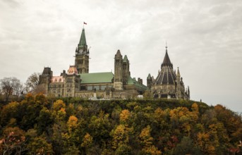 The Canadian Parliament building on a hill surrounded by colorful autumn trees, showcasing gothic