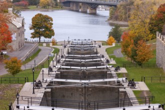 The Rideau Canal with multiple locks surrounded by autumn trees, overlooking a river and bridge in