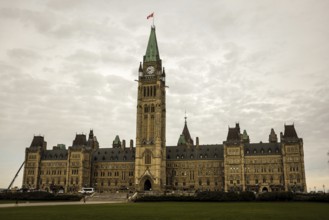 The Canadian parliament building with a central tower on a cloudy day, featuring gothic revival
