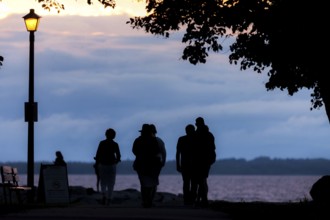 People walking along a tree-lined path at dusk under a streetlamp in Ottawa, Ontario, Canada, North