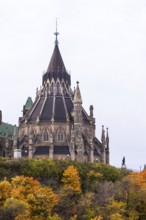 The stately Canadian Parliament Buildings with their Gothic structure with a tall spire and autumn