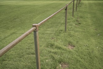 Borken, NRW, Germany, Metal railing creating a barrier along the edge of a lush green grass field