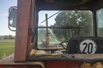 Borken, NRW, Germany, View from inside an old rusty tractor cab looking out at a green farm field