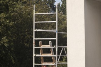 Borken, NRW, Germany, Scaffolding frame with wooden ladder against a building exterior and green