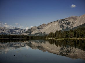 Scenic view of mountains of the Canadian Rocky Mountains mirrored in a still lake on a clear day