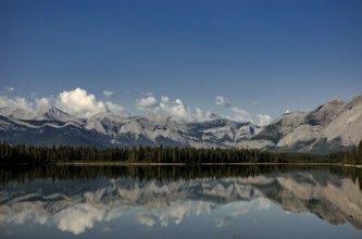 A pristine lake reflecting cloud-capped mountains of the Canadian Rocky Mountains and a peaceful