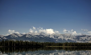 Majestic mountain range of the Canadian Rocky Mountains mirrored in a tranquil lake under a vast