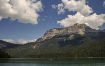 Expansive Emerald Lake surrounded by the Canadian Rocky Mountains and forests under a cloudy sky