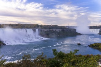 Wide view of the Bridal Veil Falls and the Horseshoe Falls with mist rising under a partly cloudy