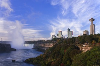 Skyline with prominent tower and the Horseshoe Falls under a bright blue sky in Niagara Falls,
