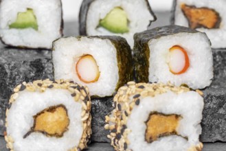 Various sushi dishes on dark grey stone surface