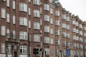 Tall red brick buildings with numerous windows form a continuous urban facade in Aarhus, Denmark,