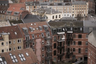 Cityscape featuring residential buildings with red tile roofs under an overcast sky in Aarhus,
