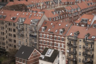 Urban scene showcasing densely packed buildings with red tile roofs on a cloudy day in Aarhus,