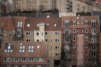 Close-up of red-tiled residential buildings with various windows and balconies in an urban setting