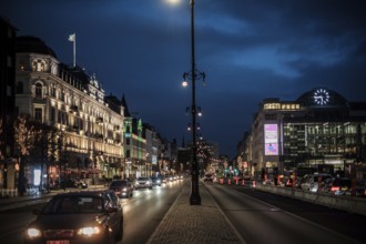 A vibrant city street in the evening with glowing lights and historic buildings in Helsingborg,