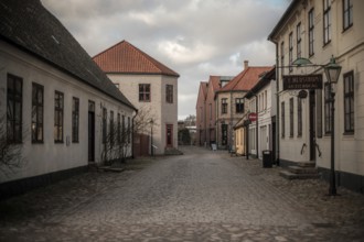 An empty street lined with buildings under a cloudy sky, vintage signs adding to the quiet
