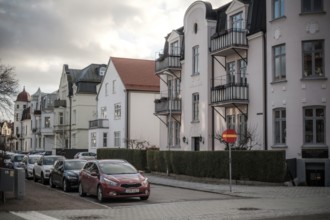 Street view of European residential buildings with parked cars and a cloudy sky in Helsingborg,