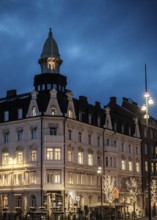 An elegant historic building with illuminated windows against a blue evening sky in Helsingborg,