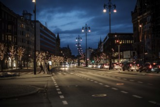 Nighttime urban road lined with illuminated trees and passing cars in Helsingborg, Sweden,