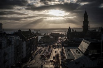 A cityscape at sunset with silhouettes of buildings and clouds overhead and looking out to the