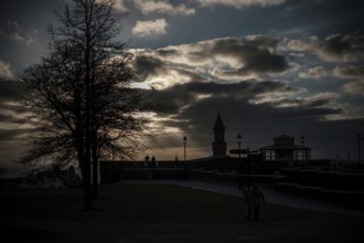 Silhouette of figures and a tower at sunset with a dramatic cloud-filled sky in Helsingborg,
