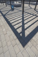 Concrete pavement, blue rubbish bin, long shadows at the state vocational school, Kempten, Allgäu,