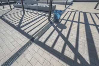 Concrete pavement, blue rubbish bin, long shadows at the state vocational school, Kempten, Allgäu,