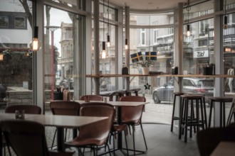 A modern cafe interior with wooden chairs and a large window view to the street in Helsingborg,