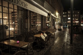 Romantic restaurant exterior at night, featuring tables and candles on a cobblestone street in