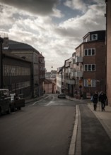 Steep street flanked by residential buildings under a dramatic cloudy sky in Helsingborg, Sweden,