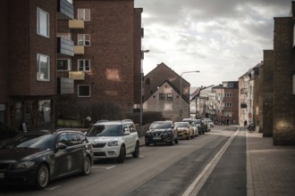 Quiet residential street with parked cars and brick buildings under clouds in Helsingborg, Sweden,