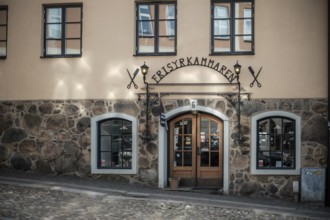 Charming building with a stone wall and decorative entrance on cobblestone street in Helsingborg,
