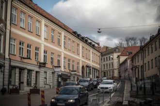 City street with parked cars and pastel-colored buildings under a cloudy sky in Helsingborg,