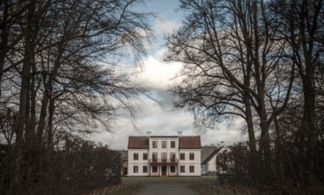 Grand manor house framed by bare trees under a blue sky in Helsingborg, Sweden, Scandinavia