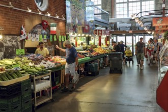 Indoor St. Lawrence Market scene with people browsing stalls filled with colorful produce in