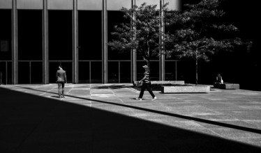 People walking in a modern urban environment with a balance of light and shadow, creating a dynamic