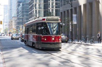 A red streetcar traveling along busy city streets in Toronto, Ontario, Canada, North America