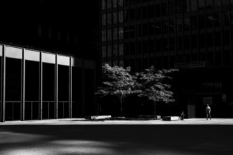 A lone person in a stark urban setting with dramatic light and shadow interplay, emphasizing