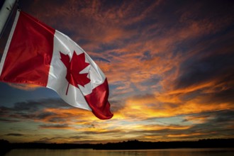 The Canadian flag waves against a vibrant sunset sky filled with colorful clouds in Muskoka,