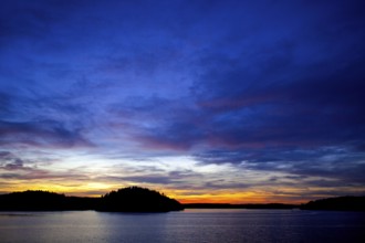 A vivid sunset over a lake, displaying a colorful horizon at twilight in Muskoka, Ontario, Canada,
