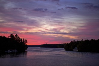 A peaceful sunset paints the sky in vibrant colors over a calm lake in Muskoka, Ontario, Canada,
