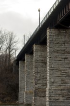 Image of a bridge with massive stone columns under an overcast sky, creating a somber industrial