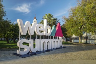 Nov 6, 2024 - Lisbon, Portugal: Big Web Summit sign displayed outdoors in park with lush palm trees