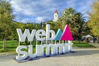 Nov 13, 2024 - Lisbon, Portugal: Large sign displaying Web Summit logo in lively park filled with