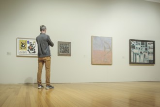 Jan 13, 2024 - Lisbon, Portugal: visitor in gray jacket and tan pants observe abstract artworks