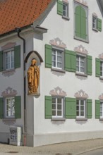 Blue sky, pointed gable house with green shutters and bishop figure, Kisslegg, Allgäu,