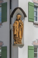 Blue sky, house with green shutters and bishop figure in corner niche, Kisslegg, Allgäu,